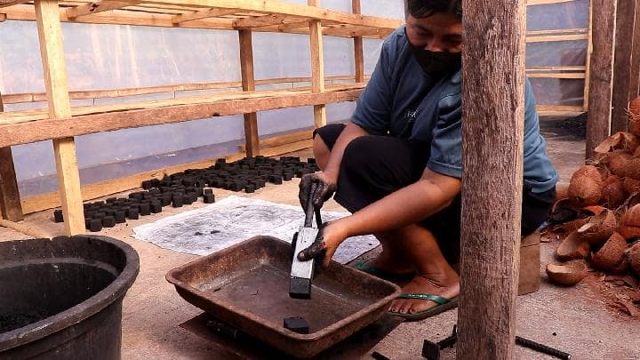 Perempuan Komunitas Wolosina Watoboki sedang menunjukkan briket berbasis tempurung kelapa yang telah siap pakai, setelah dijemur selama lima hari di Rumah Energi Matahari. (Dokumentasi: Regina Azi)